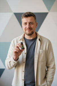 gemini-2.5-flash-image_Professional_presentation_photo_of_a_man_holding_a_small_essential_oil_bottle_be-0